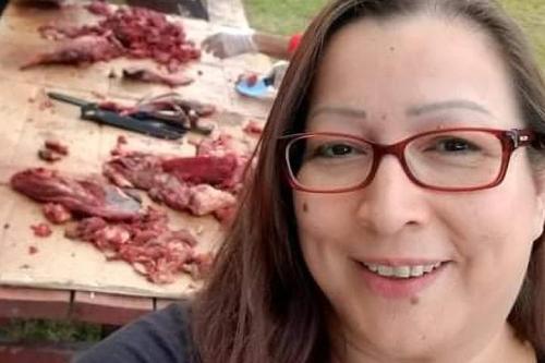 Woman taking selfie in front of table where meat is being prepared for smoking