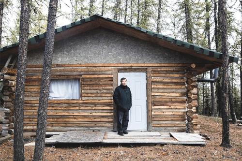 Man standing outside log cabin
